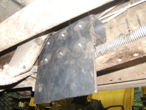 1993 Ford Bronco - Close-up of a custom metal bracket attached to the undercarriage of a vehicle, showing suspension and tire details.
