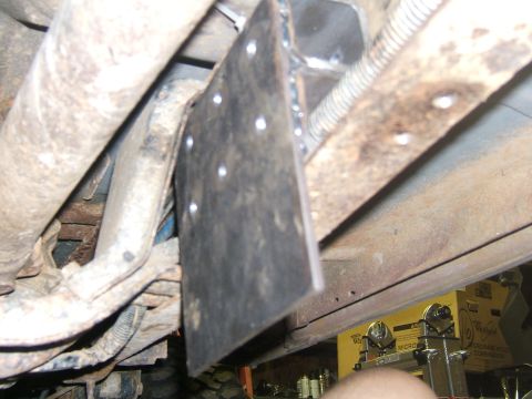 1993 Ford Bronco - A close-up view of a custom metal plate installation on the undercarriage of a vehicle, showing bolted connections and surrounding mechanic…