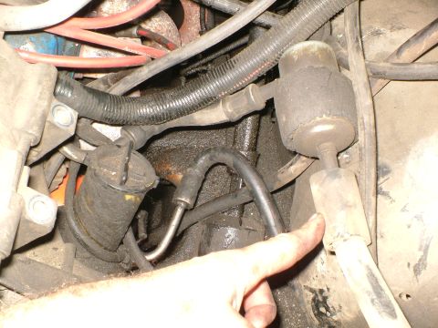 1989 Ford Bronco - Close-up of engine bay components, including hoses and a filter, with a finger pointing.
