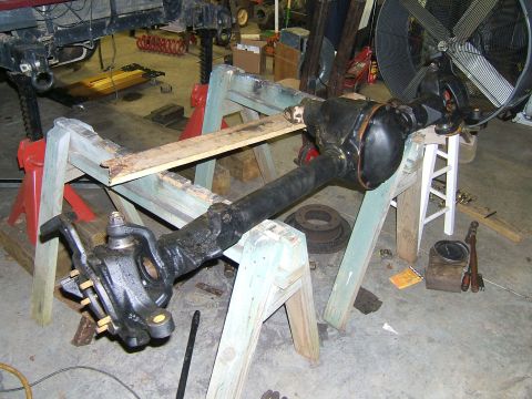 1993 Ford Bronco - A disassembled front axle assembly is supported by sawhorses in a garage setting.