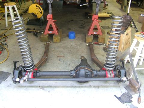 1993 Ford Bronco - A vehicle's front axle and suspension components are disassembled and supported by jack stands in a workshop.
