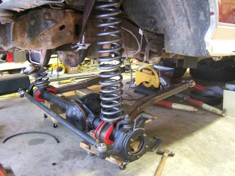 1993 Ford Bronco - Close-up view of a vehicle's suspension system undergoing modification, showing heavy-duty springs and differential components.
