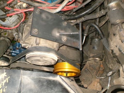 1989 Ford Bronco - Close-up view of engine components, including the AC compressor and a gold-colored pulley.