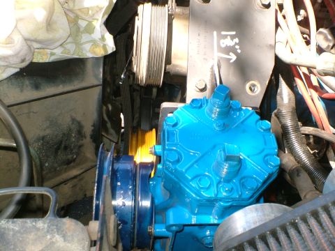 1989 Ford Bronco - Close-up of a blue engine compressor with drive belts and pulleys, part of an engine bay.