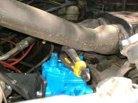 1989 Ford Bronco - A close-up view of an engine bay shows a newly painted blue compressor with tools on it.