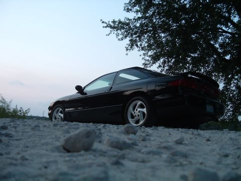 1995 Ford Probe - A black 1995 Ford Probe is parked on a gravel lot under a large tree during twilight.
