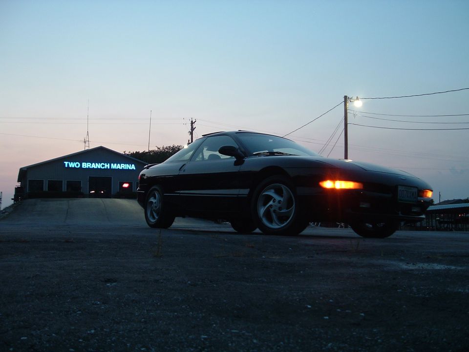 1995 Ford Probe parked outside Two Branch Marina at dusk
