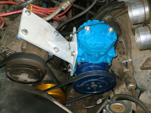 1989 Ford Bronco - A freshly painted blue York-style AC compressor with a dark blue clutch pulley, mounted to the engine via a fabricated aluminum bracket sec…
