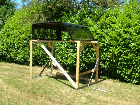 1989 Ford Bronco - A black Ford Bronco hardtop is displayed on a custom wooden stand in a grassy yard with green bushes in the background.