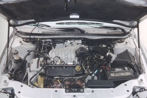 V6 engine bay of white Ford sedan with battery and air intake