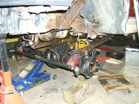 1993 Ford Bronco - Close-up view of front axle and suspension components, likely during a repair or modification, with various tools and supports visible.