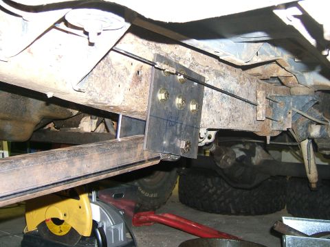 1993 Ford Bronco - Close-up view of a modified vehicle frame, showing a newly installed bracket with bolts and visible suspension parts.