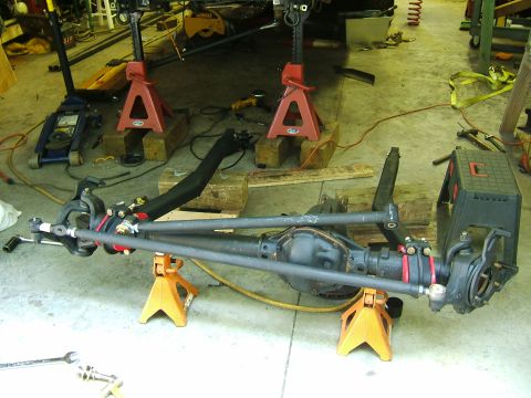 1993 Ford Bronco - Front axle assembly, likely for a 4x4 vehicle, is supported by jack stands in a garage.