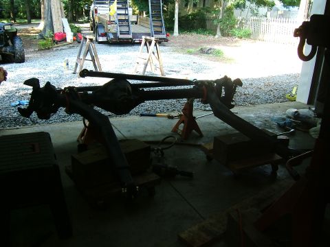 1993 Ford Bronco - A vehicle's front axle assembly is supported by jack stands in a garage setting.
