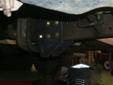 1993 Ford Bronco - Close-up view of a vehicle's undercarriage, focusing on a bolted metal bracket and suspension parts.