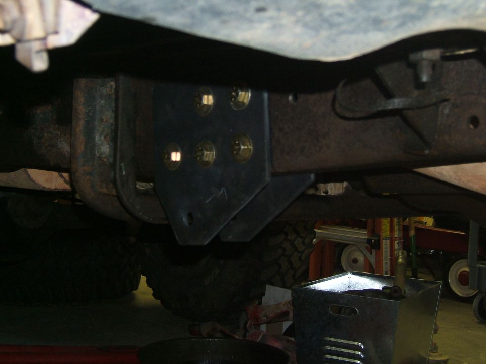 Undercarriage with a black metal bracket bolted to the frame, showing large tires and suspension components