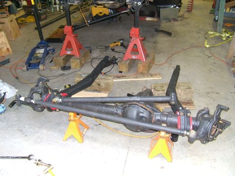 1993 Ford Bronco - A disassembled front axle assembly is supported by jack stands in a workshop environment.