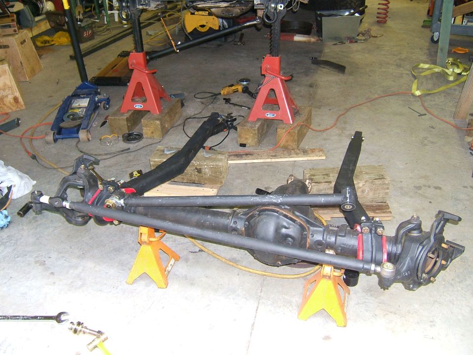 Front axle assembly on jack stands in a garage with tools around