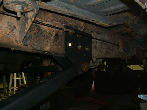 1993 Ford Bronco - A close-up view of a black metal bracket attached to the rusty undercarriage of a vehicle.