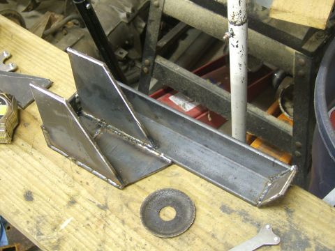 1993 Ford Bronco - A custom metal bracket, likely for automotive use, sits on a wooden surface next to tools.