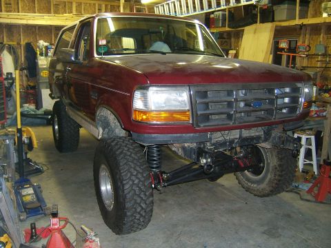 1993 Ford Bronco - This modified Ford Bronco is undergoing suspension work in a garage setting.