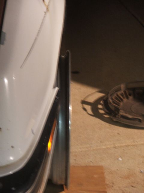1990 Dodge Shadow - Close-up of a white car's fender and wheel, showing a chrome rim and tire.