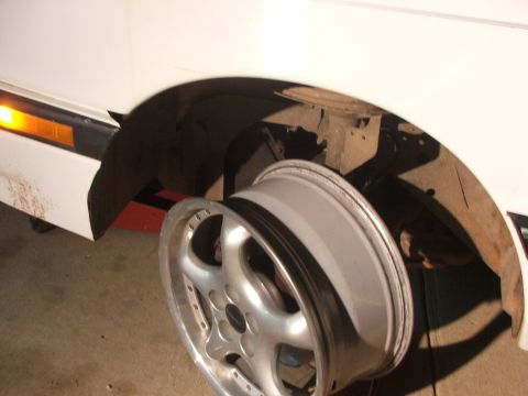 1990 Dodge Shadow - Wheel removed from vehicle, showing the fender well and suspension components.