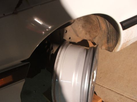 1990 Dodge Shadow - A white rim is positioned near the wheel well of a vehicle.