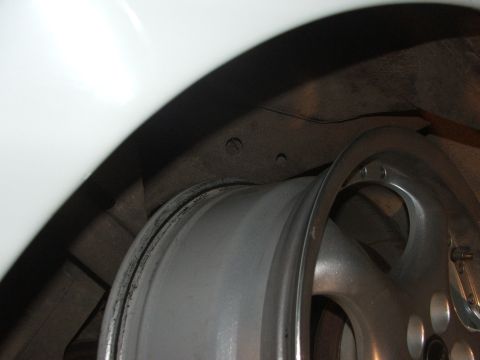 1990 Dodge Shadow - Detail of a silver alloy wheel and the white fender liner of a vehicle.