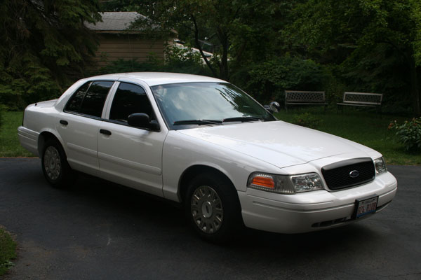 White 2003 Ford Crown Victoria, 3q front view. Grille and headlights are characteristic of this model year