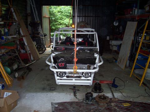 1989 Ford Bronco II - A custom-built off-road vehicle is suspended by a hoist inside a cluttered garage.