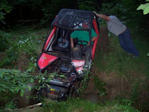 1989 Ford Bronco II - Off-road buggy is stuck in a ditch with a person trying to push it out.