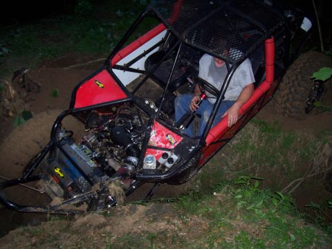 1989 Ford Bronco II - An off-road buggy is stuck in a muddy ditch, its engine exposed to the elements.