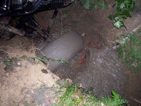 1989 Ford Bronco II - A vehicle appears to be stuck in a muddy ditch, with its tire submerged in the mire.