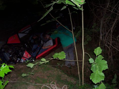 1989 Ford Bronco II - An off-road vehicle appears to be stuck or overturned in a wooded area at night, with occupants visible inside.