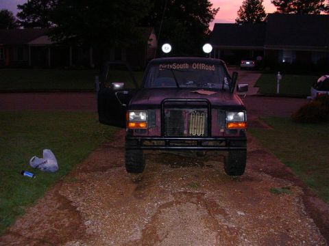 1989 Ford Bronco II - A 1989 Ford Bronco II with its door open sits on a gravel driveway under a twilight sky.