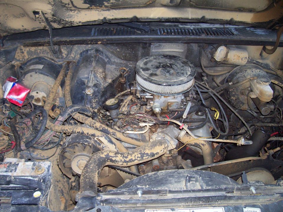 Engine bay with carburetor, fan, and lots of dirt and wiring