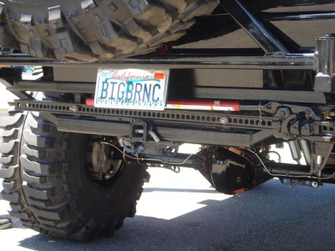 1991 Ford Bronco - Rear view of a modified off-road vehicle showing its large tire, license plate, and Hi-Lift jack.