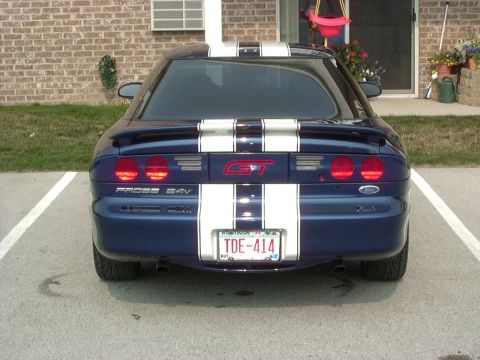 1995 Ford Probe - The rear of a blue 1995 Ford Probe GT with white racing stripes is visible, parked in a lot.