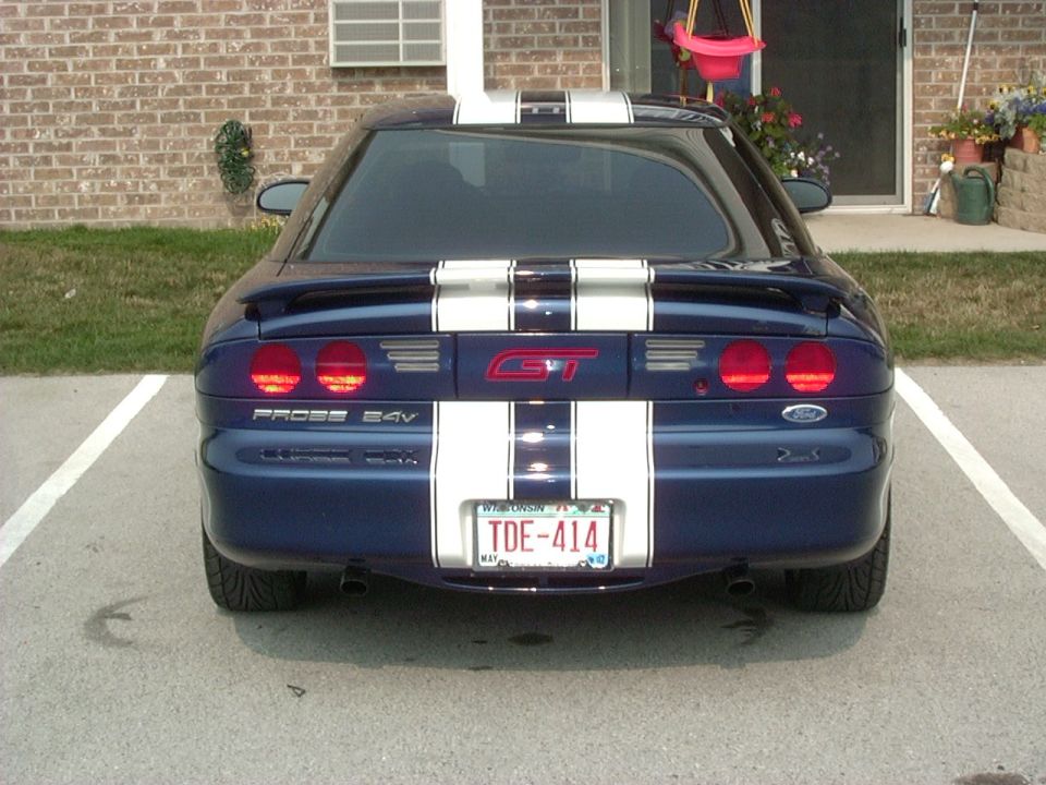 Blue 1995 Ford Probe GT with white racing stripes parked in a lot, rear view
