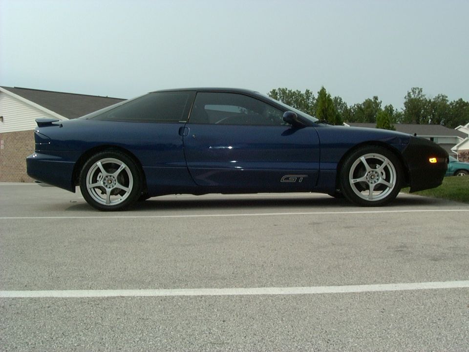 blue 1995 Ford Probe GT parked on asphalt, side view. Has aftermarket wheels and a black bra on the front