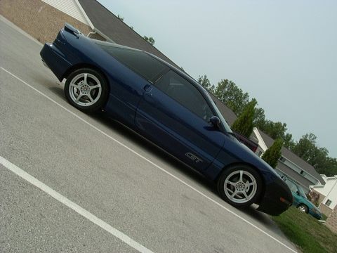 1995 Ford Probe - A blue 1995 Ford Probe GT is parked on a street, with another car visible in the background.