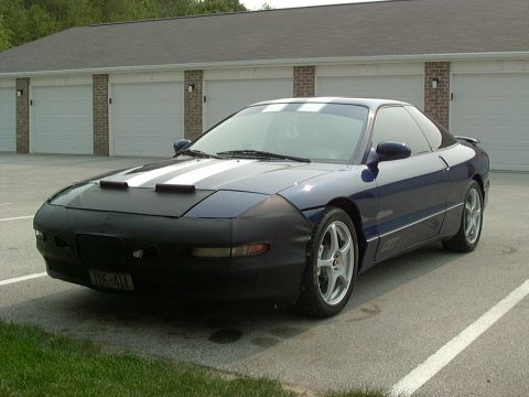 1995 Ford Probe - A dark blue Ford Probe is parked outside a building, racing stripes and a car bra.