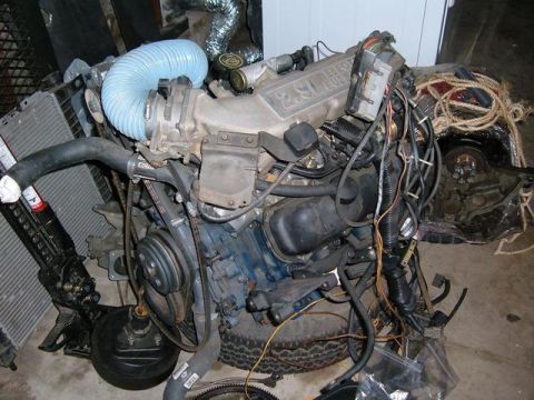 1985 Ford Bronco II - A disassembled Ford 2.9L V6 engine sits on the floor next to a radiator and other parts.
