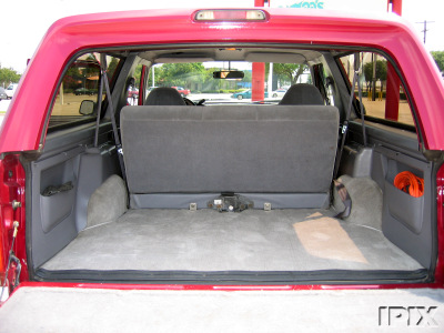 1995 Ford Bronco - The rear cargo area of a red Ford Bronco, showing the folded-down rear seats and interior storage compartments.