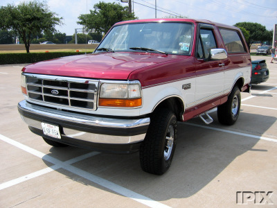 1995 Ford Bronco - This two-tone Ford Bronco is parked in a lot under a cloudy sky.