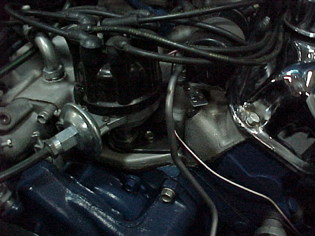 Engine bay close-up with black distributor, spark plug wires, and blue engine block