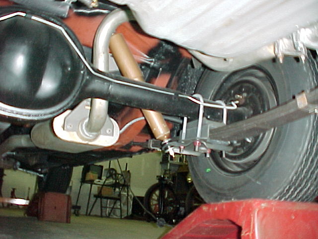 Underside of vehicle showing rear axle, differential, leaf springs and tire on a lift