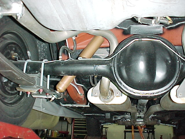 Underside rear axle with black differential, tan shocks and exhaust muffler