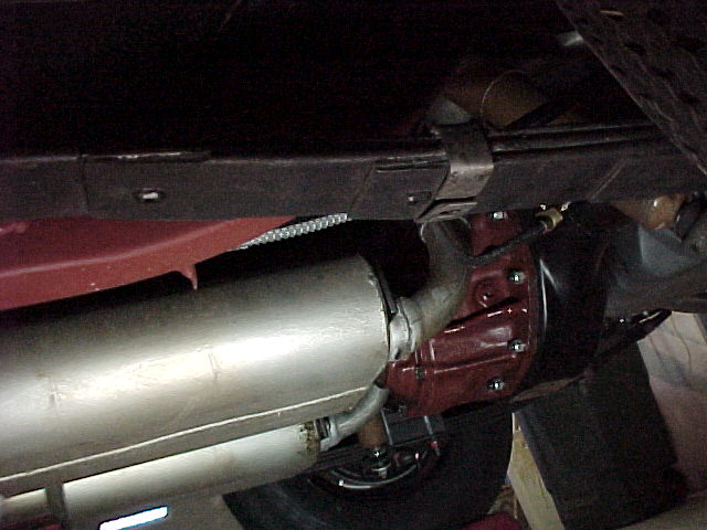 Underside rear differential with maroon housing, driveshaft, and silver muffler